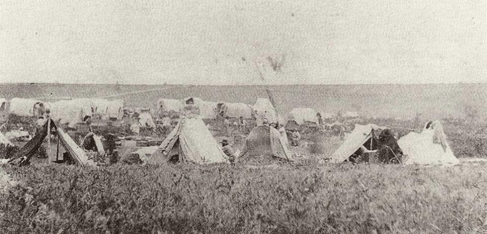 A black and white photo of a group of tents in a field.