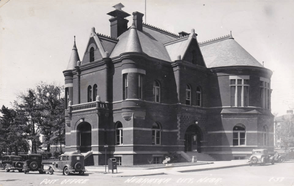 A black and white photo of a large brick building called post office