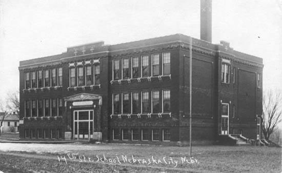 A black and white photo of a large brick building with a chimney.