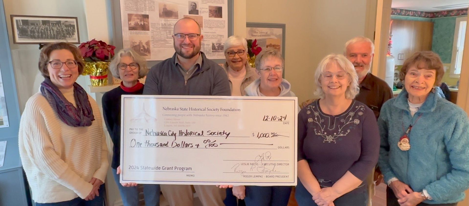 A group of people are posing for a picture while holding a large check.