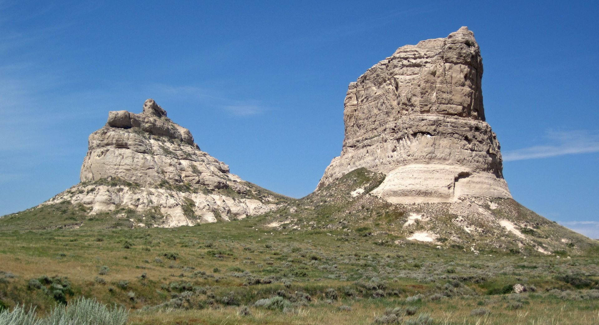 Two large rock formations in the middle of a grassy field