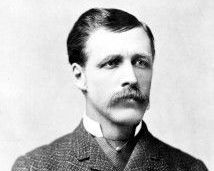 A black and white photo of a man with a mustache in a suit.