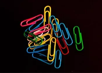 Colorful paperclips scattered on a black background.