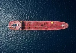 Aerial view of a red oil tanker on dark blue ocean water.