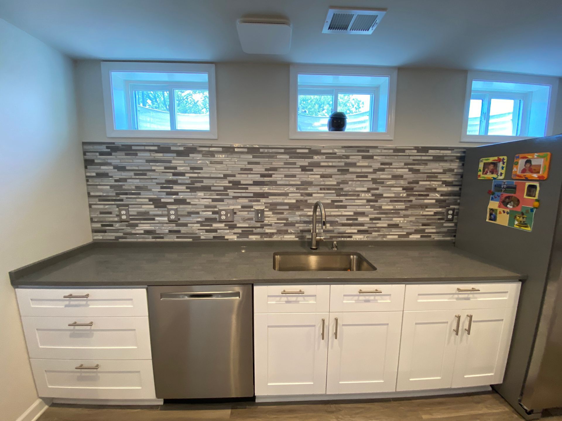 A kitchen with stainless steel appliances , white cabinets , a sink and a refrigerator.