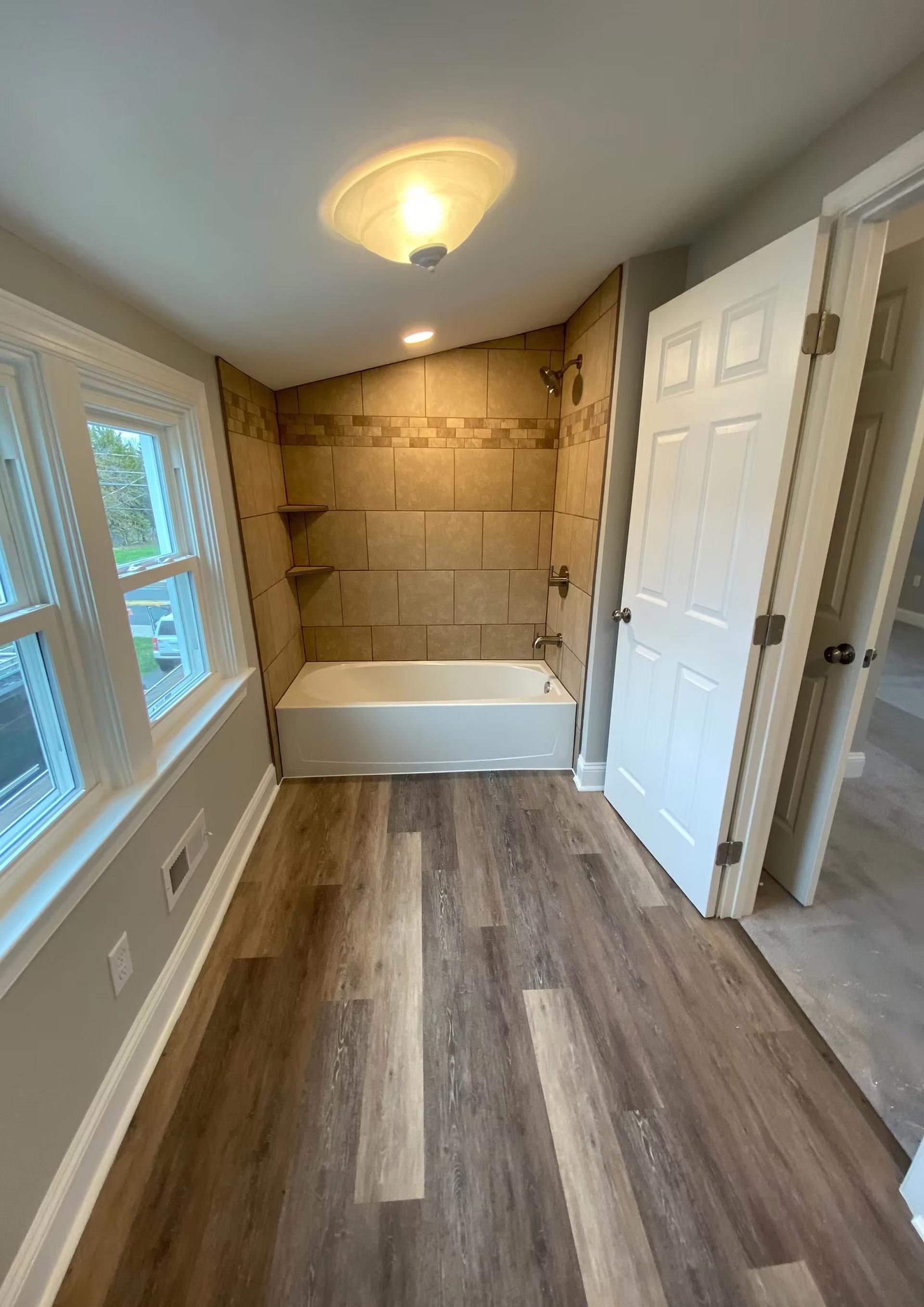 A bathroom with a tub , shower , and window.