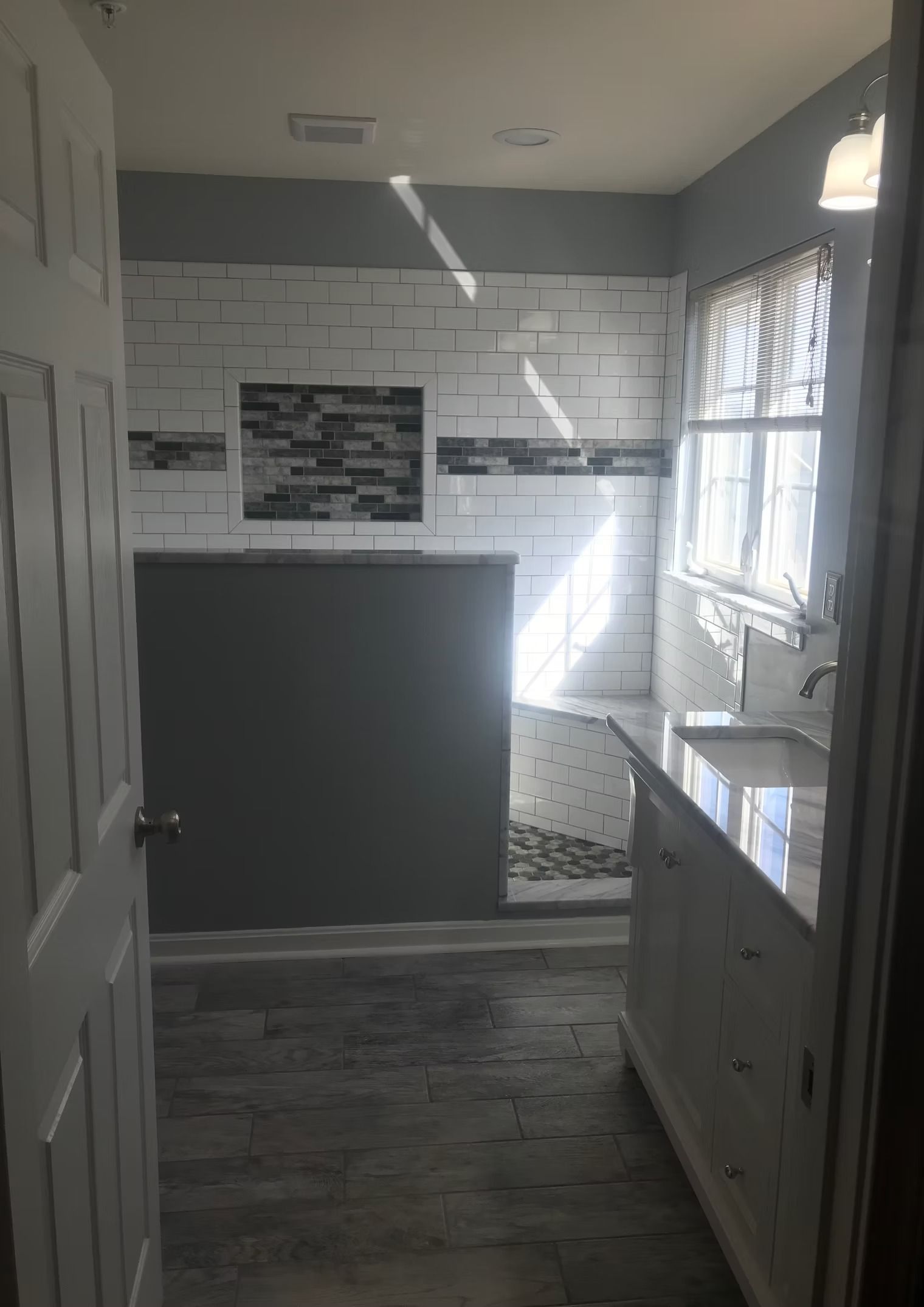 A bathroom with a sink , shower , and window.