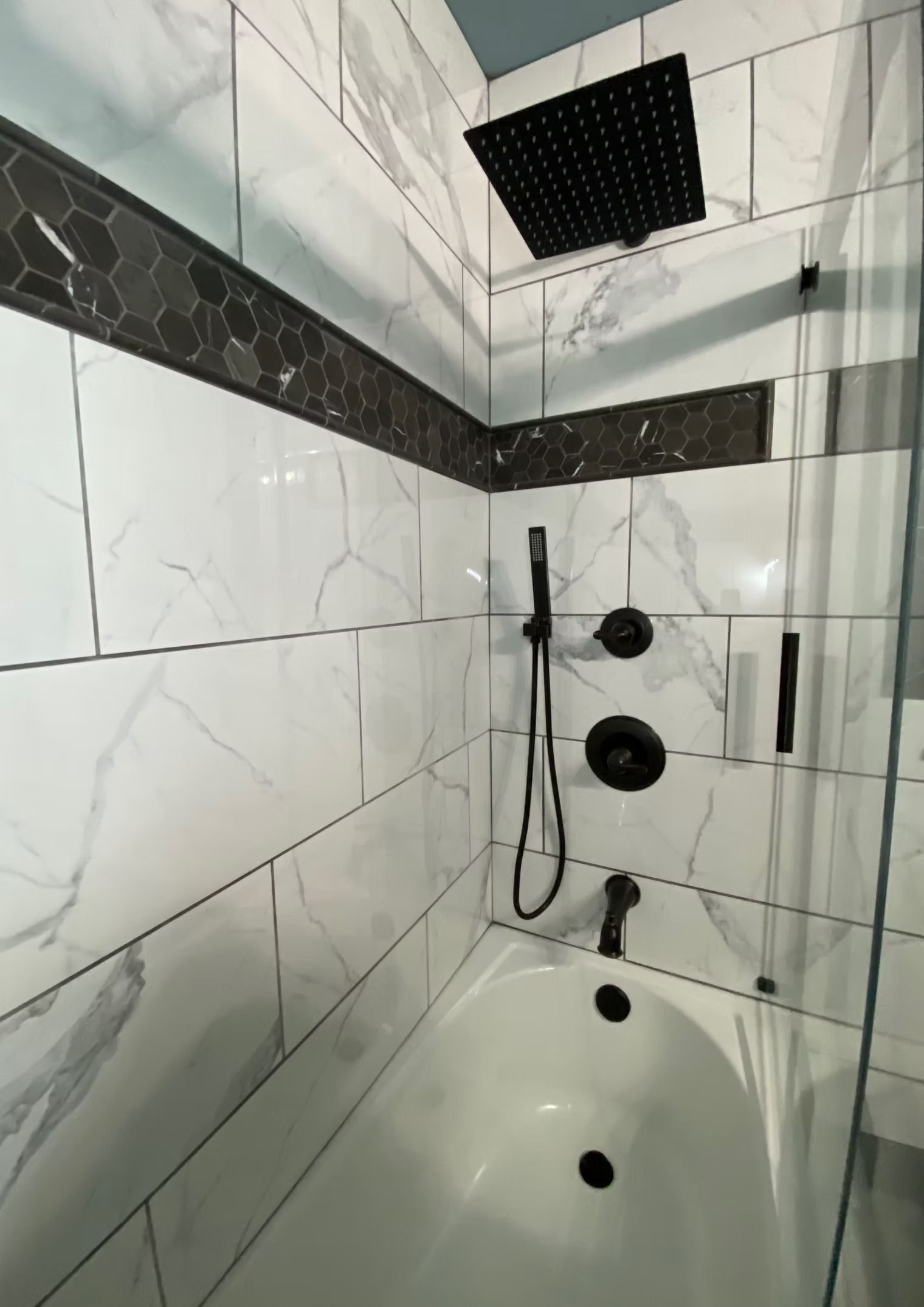 A bathroom with a bathtub and a shower head.