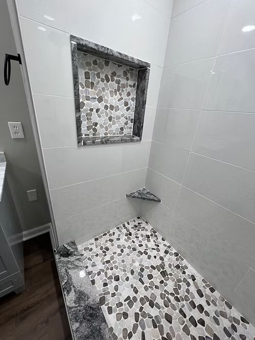 A bathroom with a walk in shower and a built in shelf.