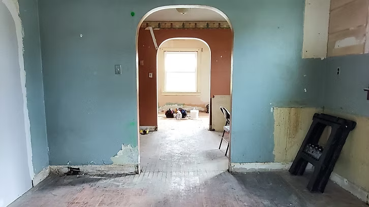 A room with a ladder in the middle of it and a window.