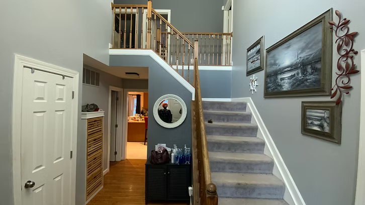 A hallway with stairs and a mirror on the wall