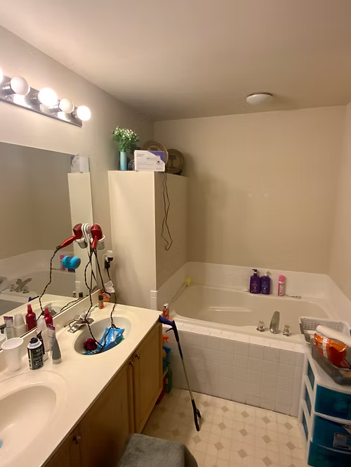 A bathroom with a tub , sink , mirror and hair dryers