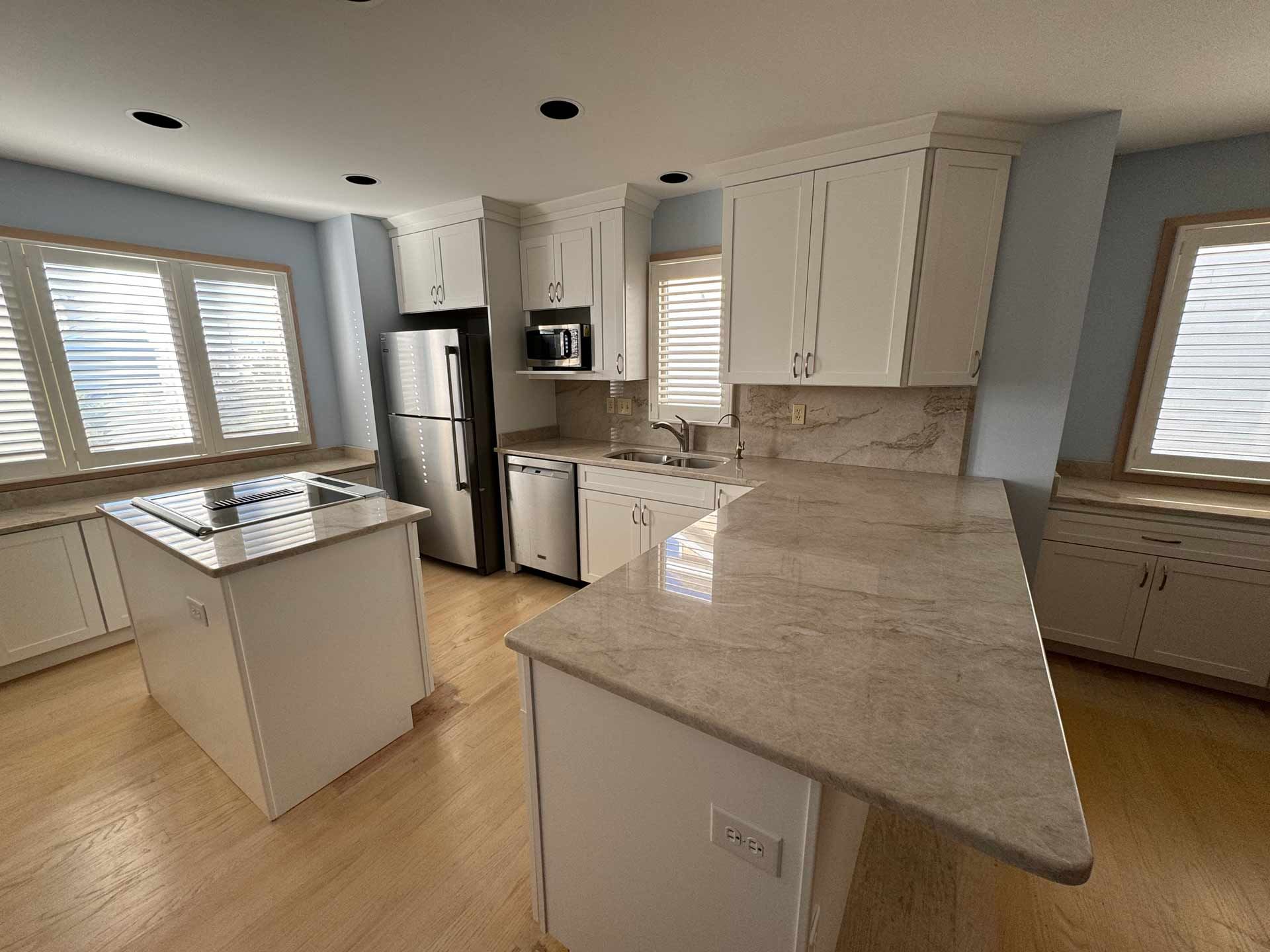 A kitchen with white cabinets , granite counter tops and stainless steel appliances.
