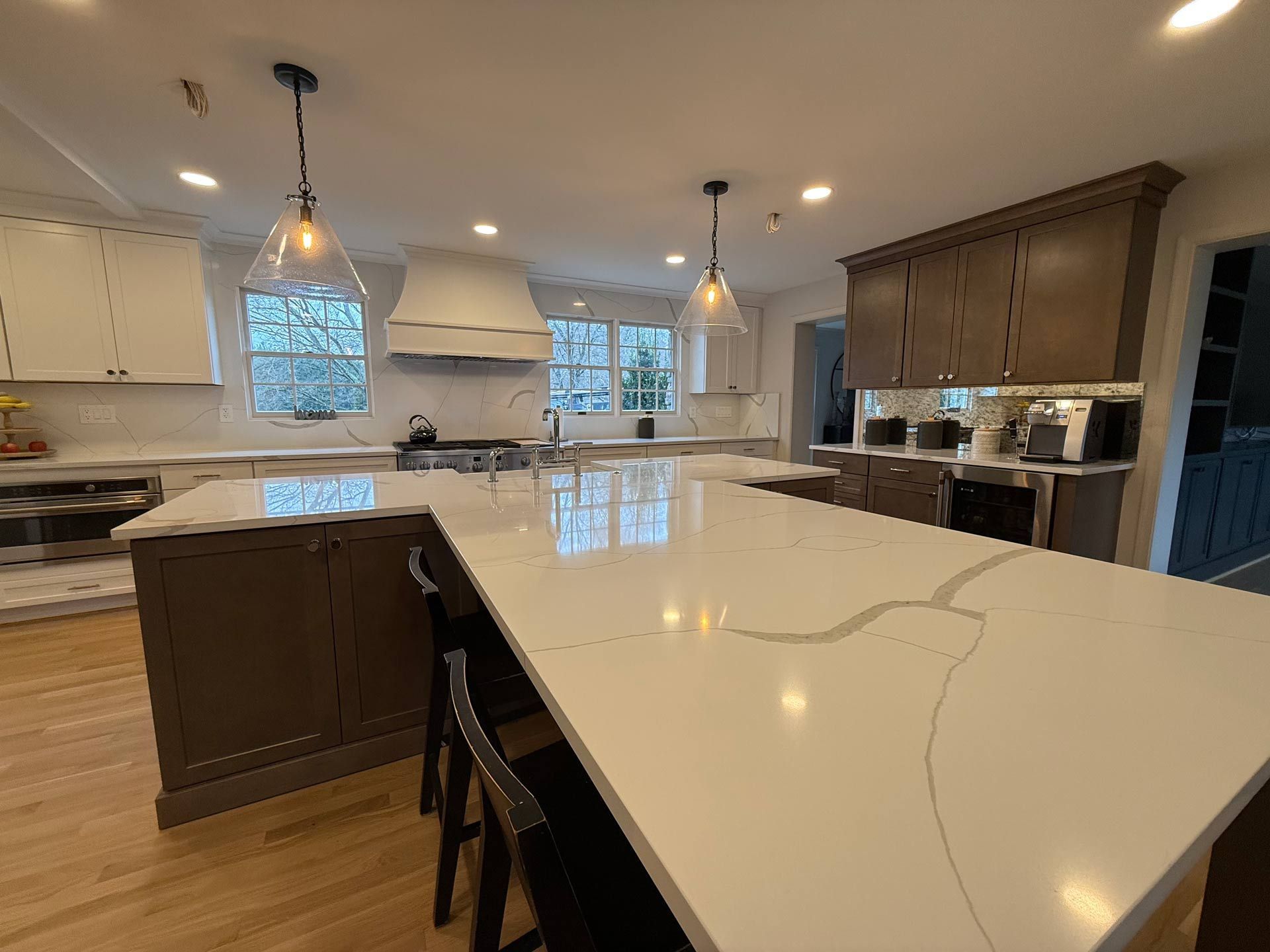 A kitchen with a large island and white counter tops.