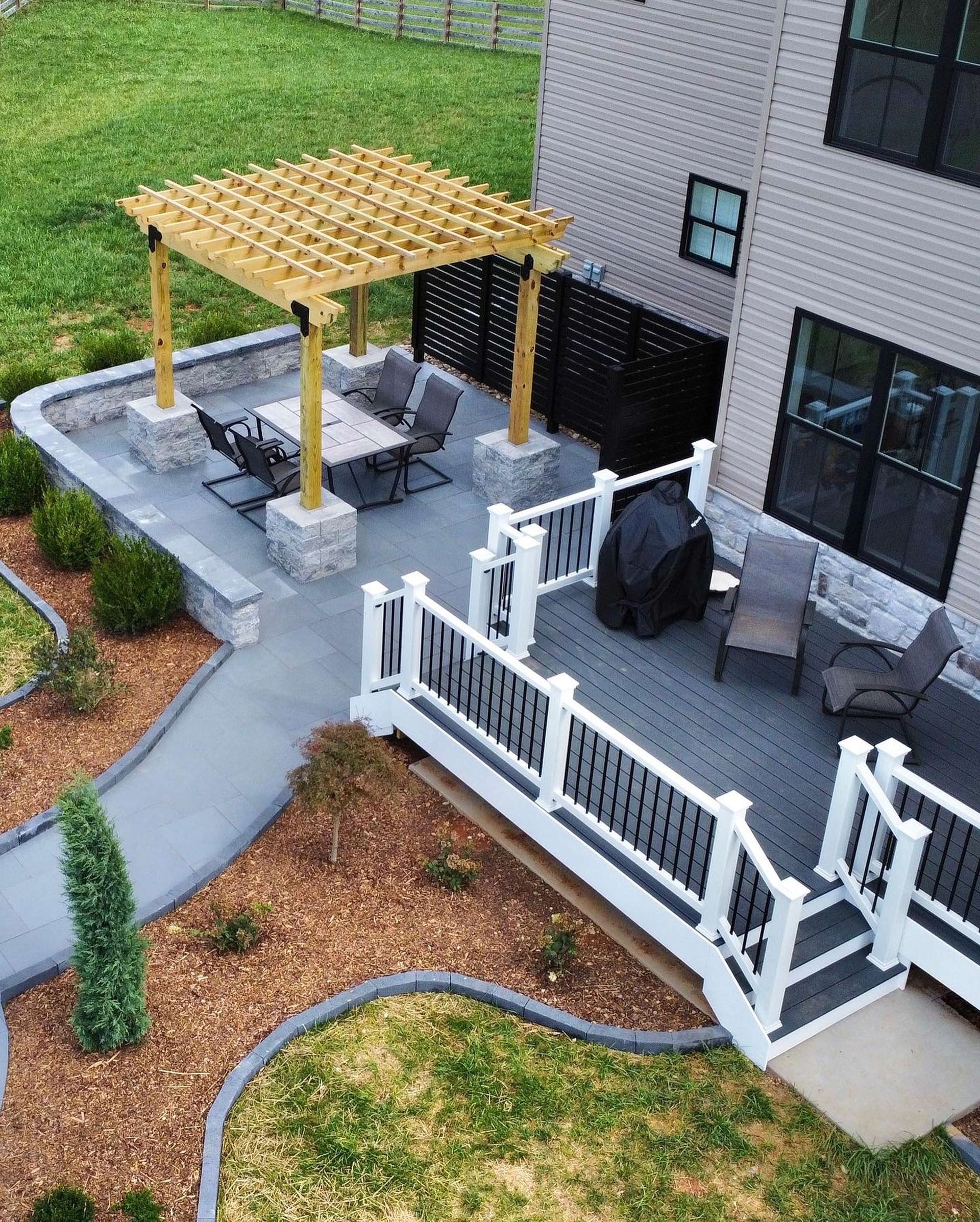 An aerial view of a deck with a pergola and chairs in front of a house.