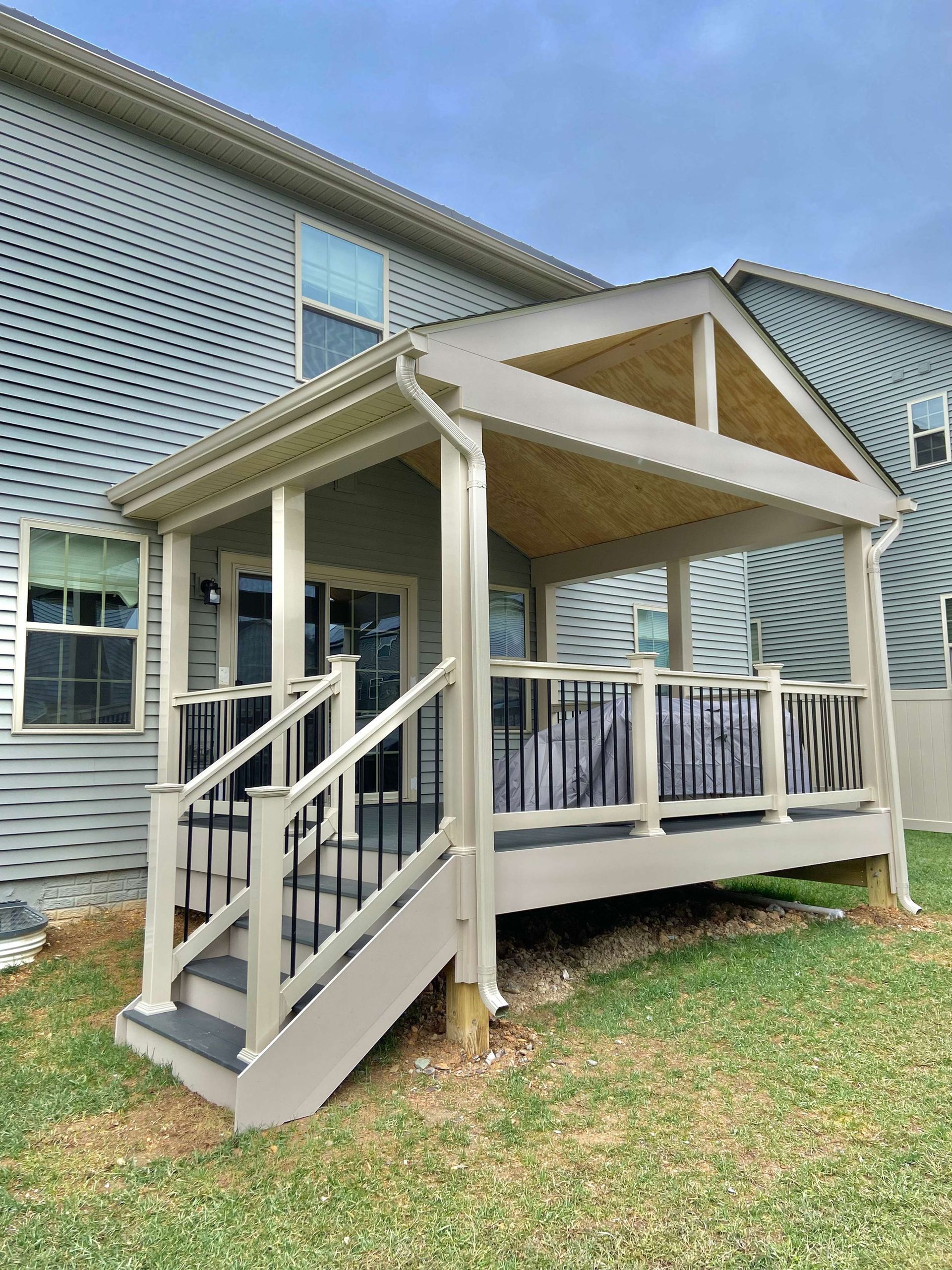 A deck with stairs leading up to it is in the backyard of a house.