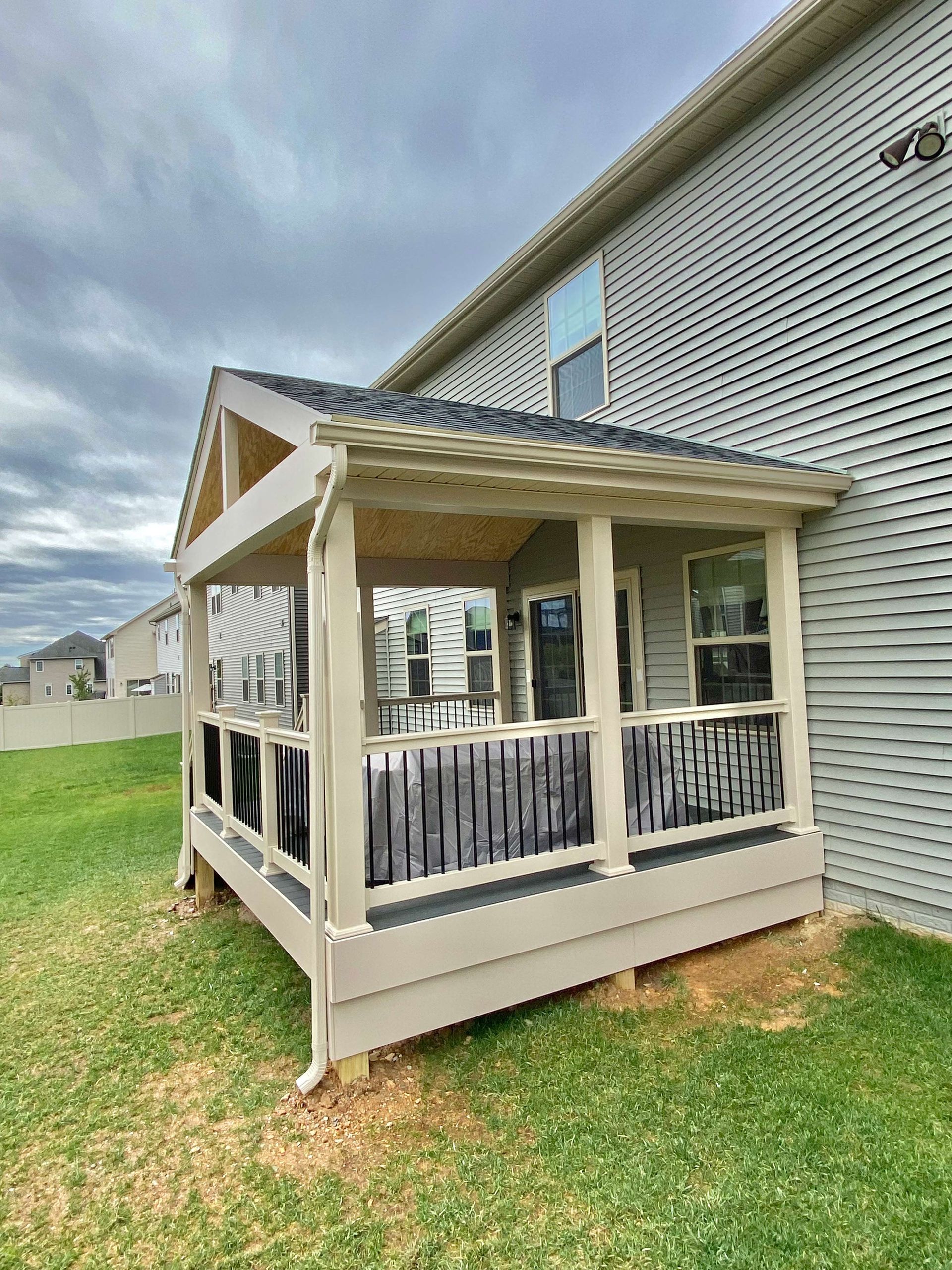 A porch with a roof is sitting in front of a house.