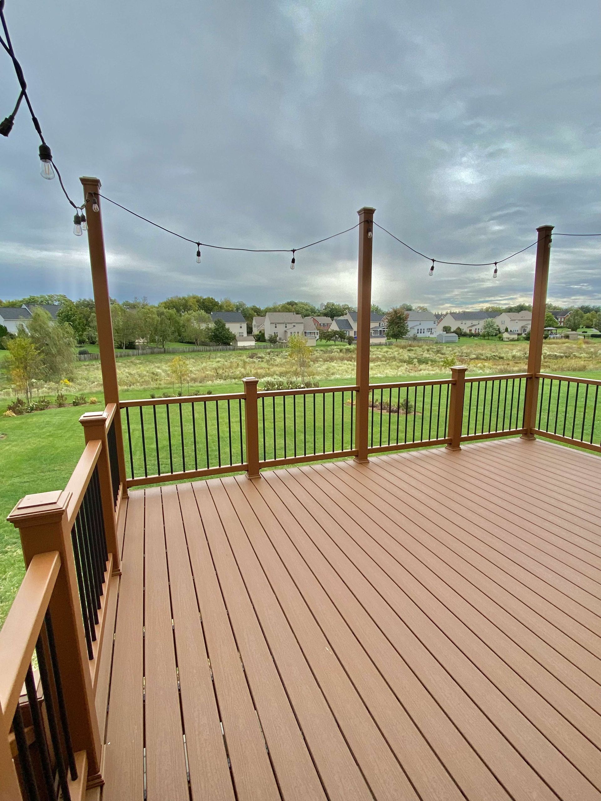 An empty deck with a wooden railing and a view of a field.