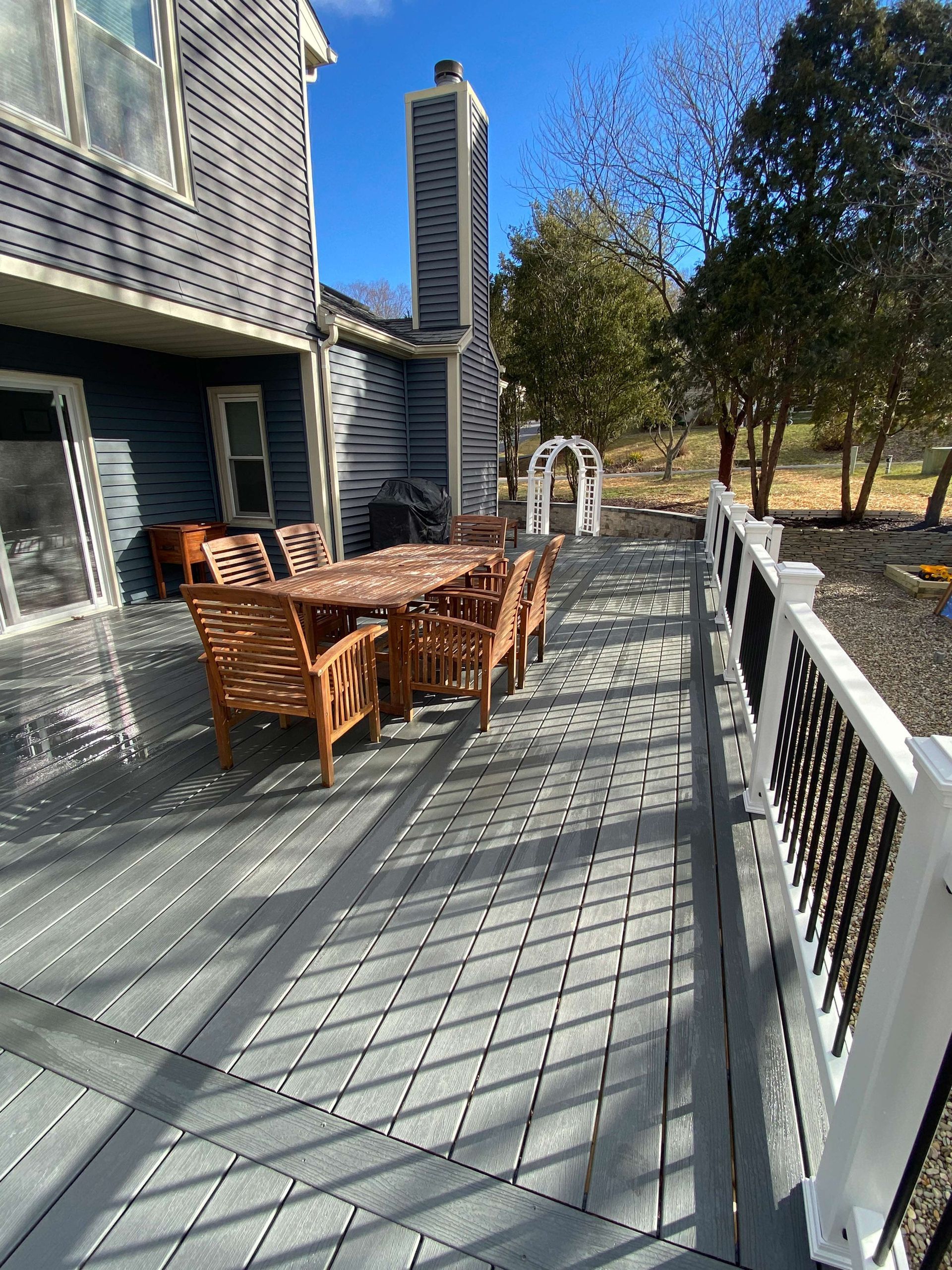 A deck with a table and chairs on it in front of a house.
