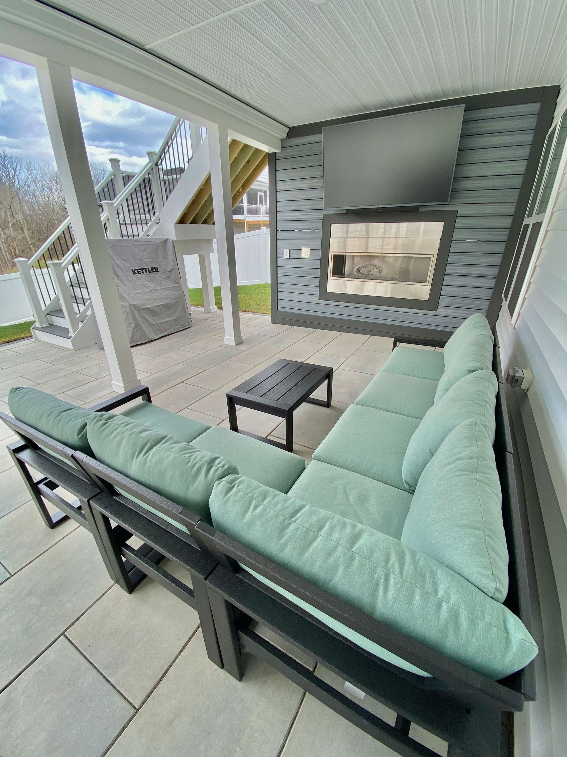 A patio with a couch , table and fireplace.