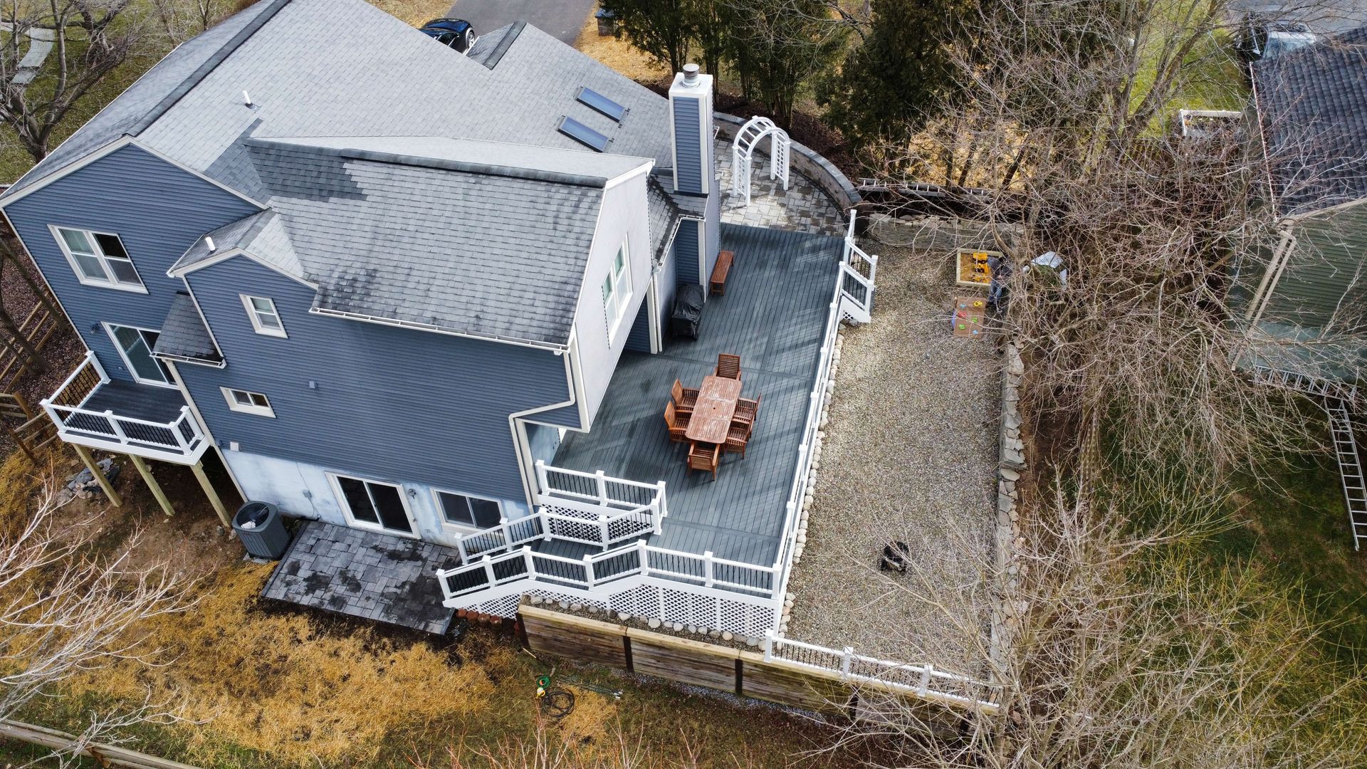 An aerial view of a house with a large deck and a table and chairs on it.