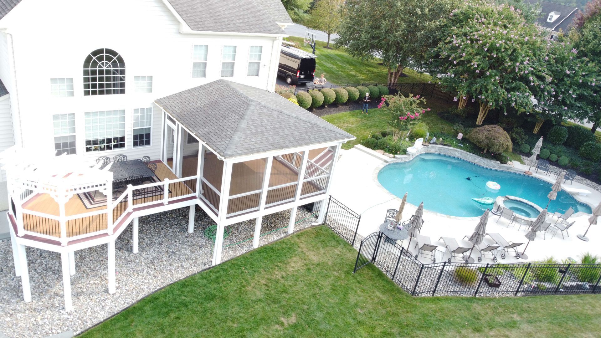 An aerial view of a house with a swimming pool and a screened in porch.