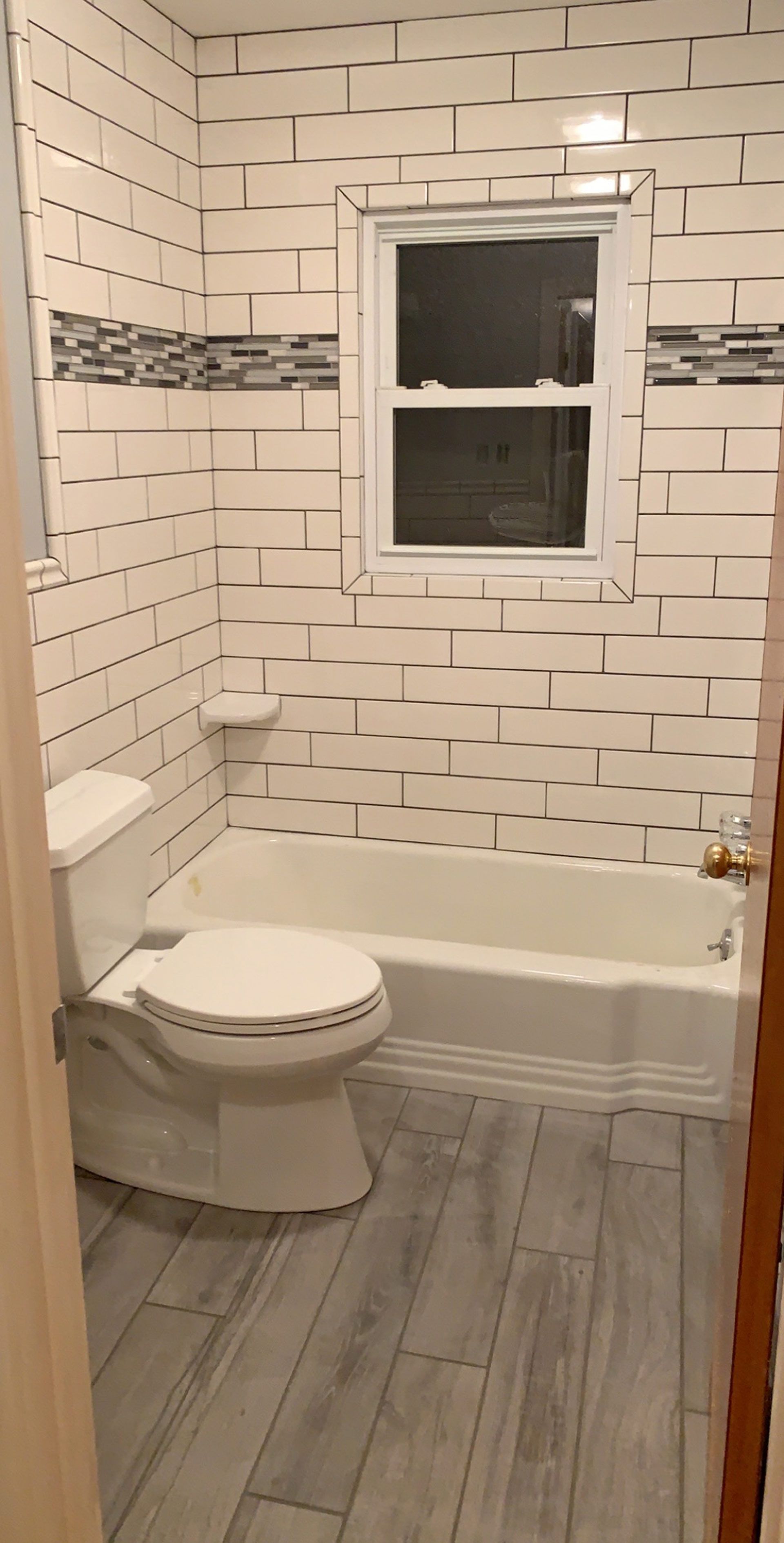A bathroom with a toilet , tub , and window.