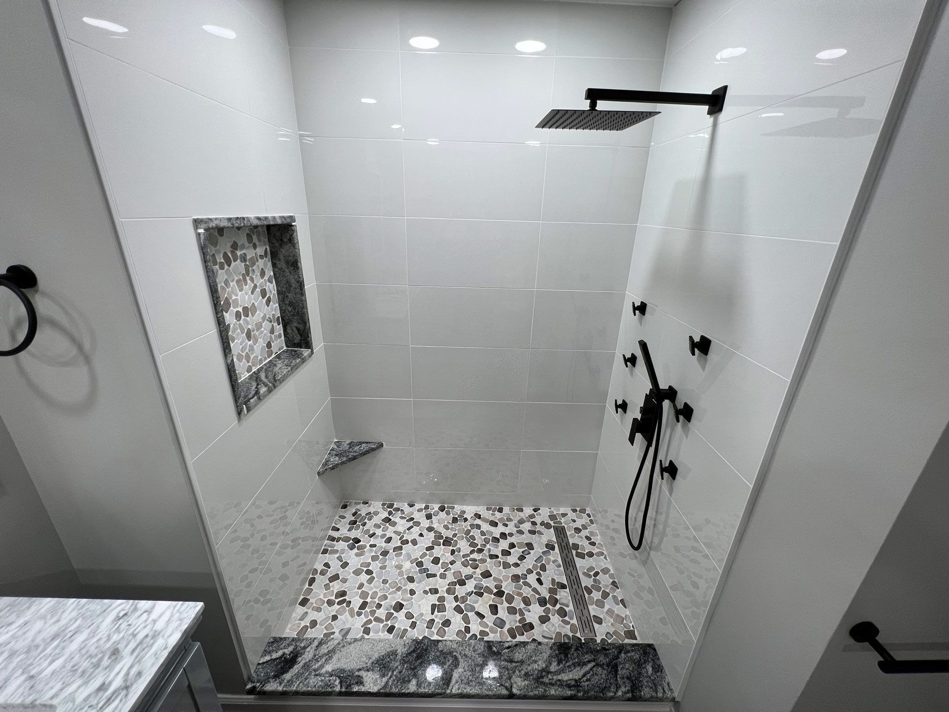 A bathroom with a walk in shower and a black shower head.
