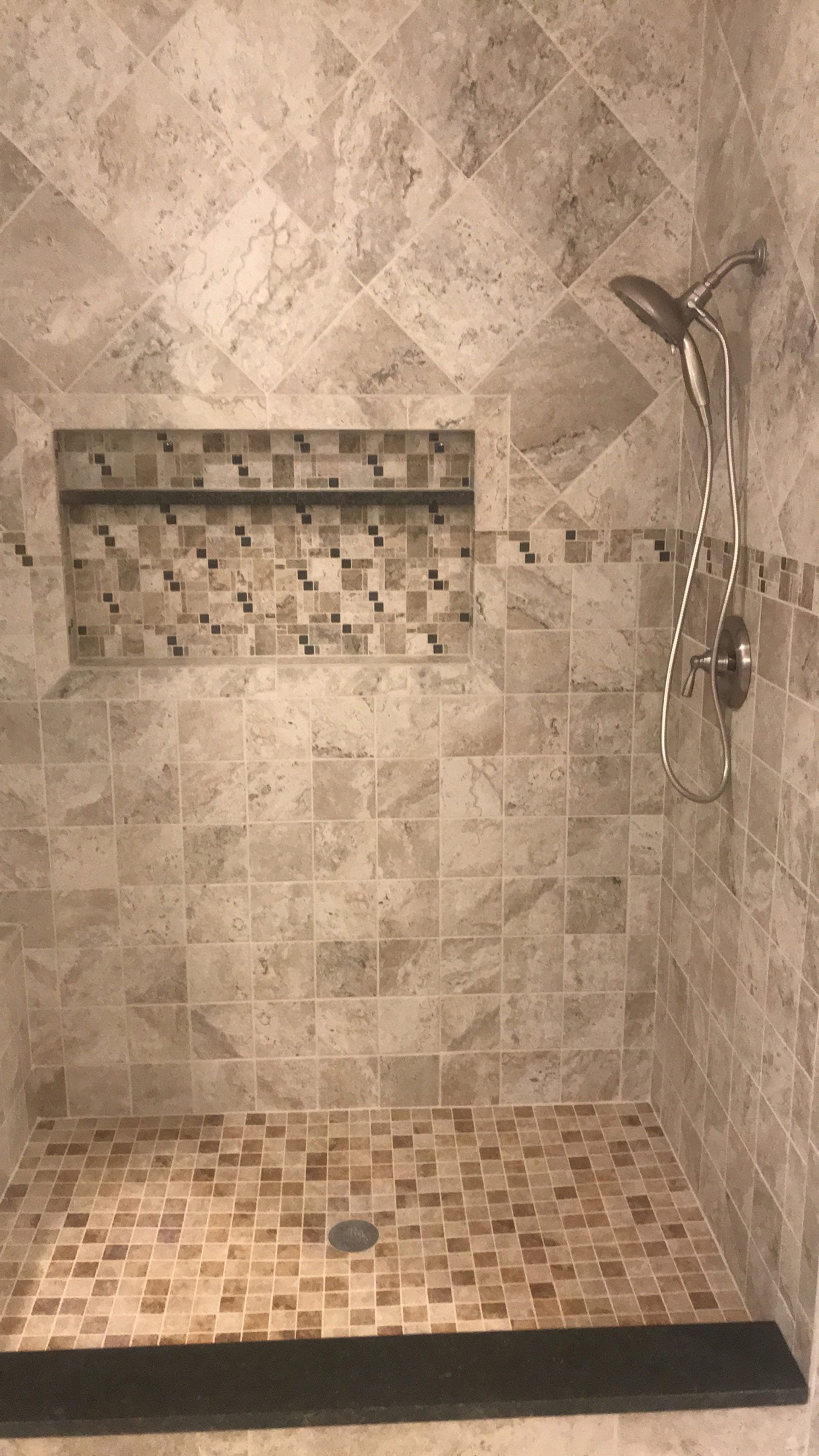 A walk in shower with a tiled floor and a shower head.