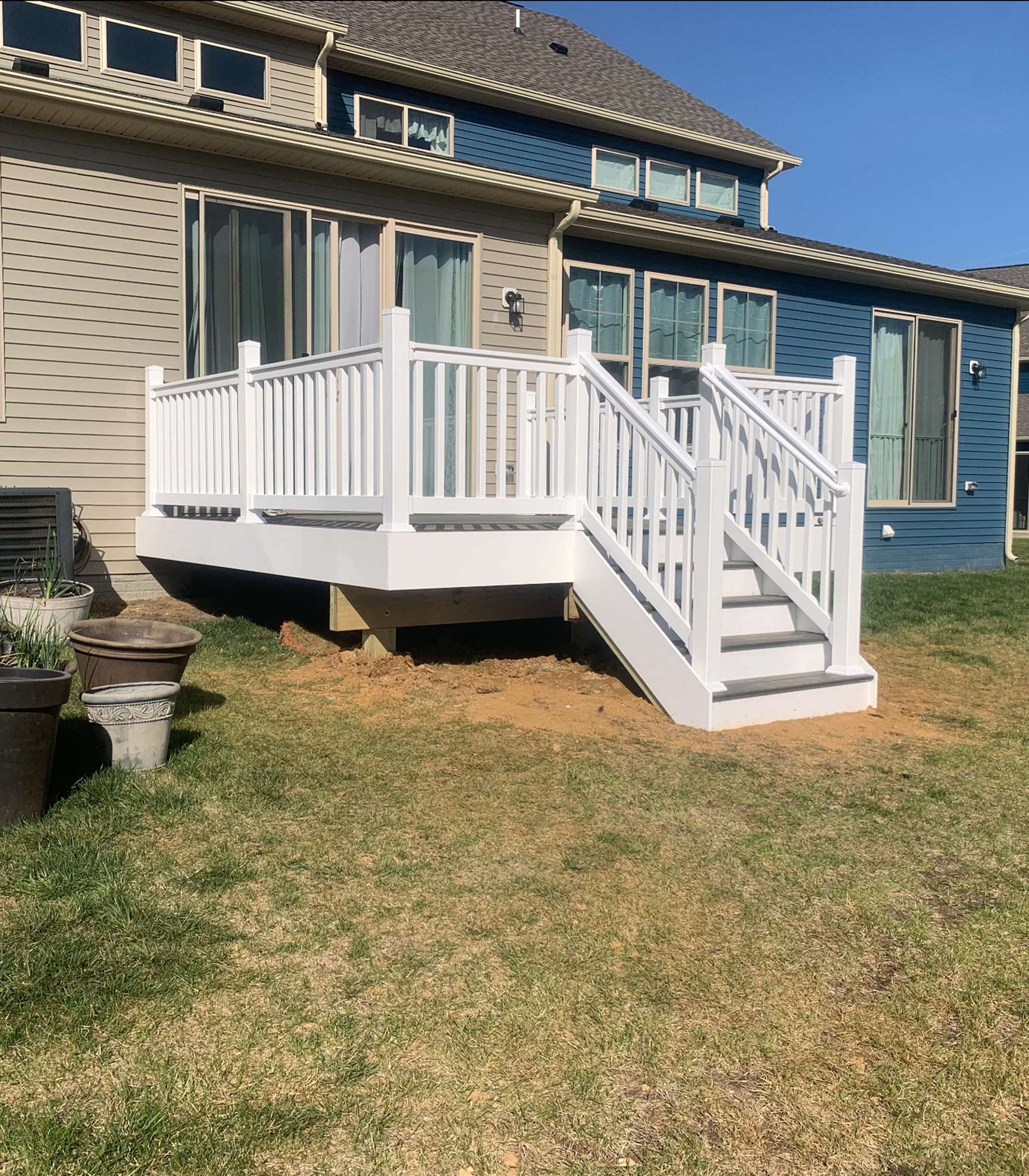 A white deck with stairs is in the backyard of a house.