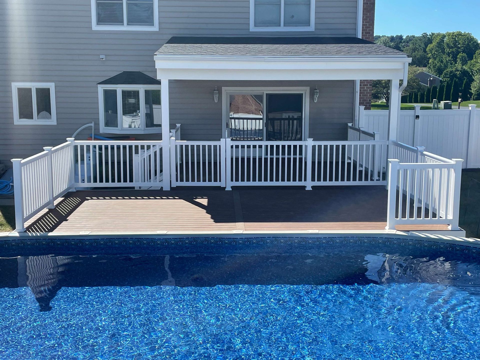 A house with a large deck and a pool in front of it