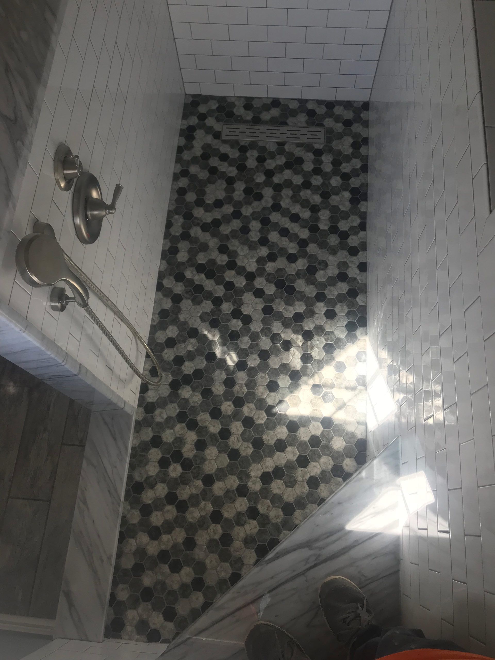 A bathroom with a walk in shower with a black and white tile floor.