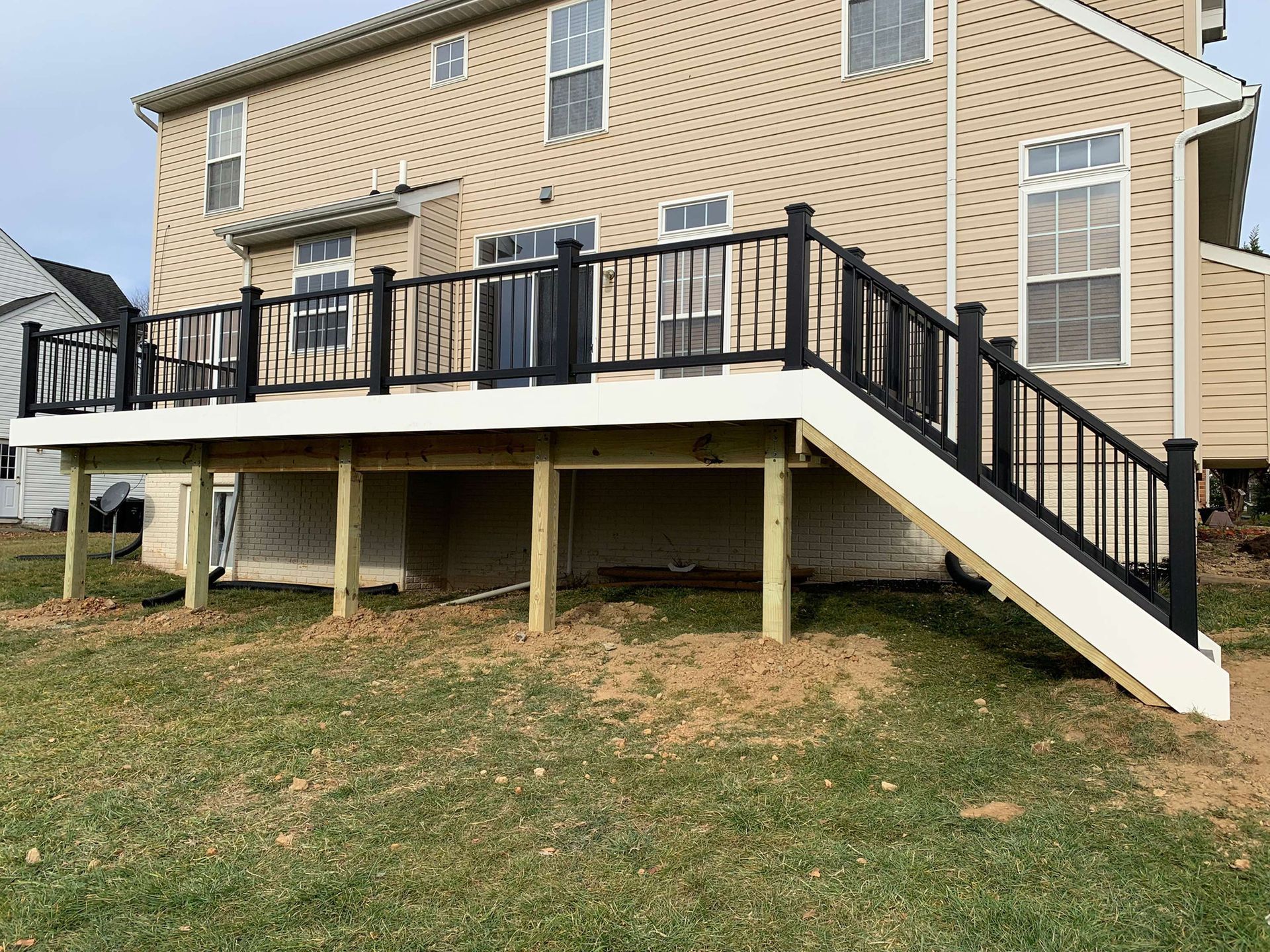 A large deck with stairs leading up to it is in front of a house.