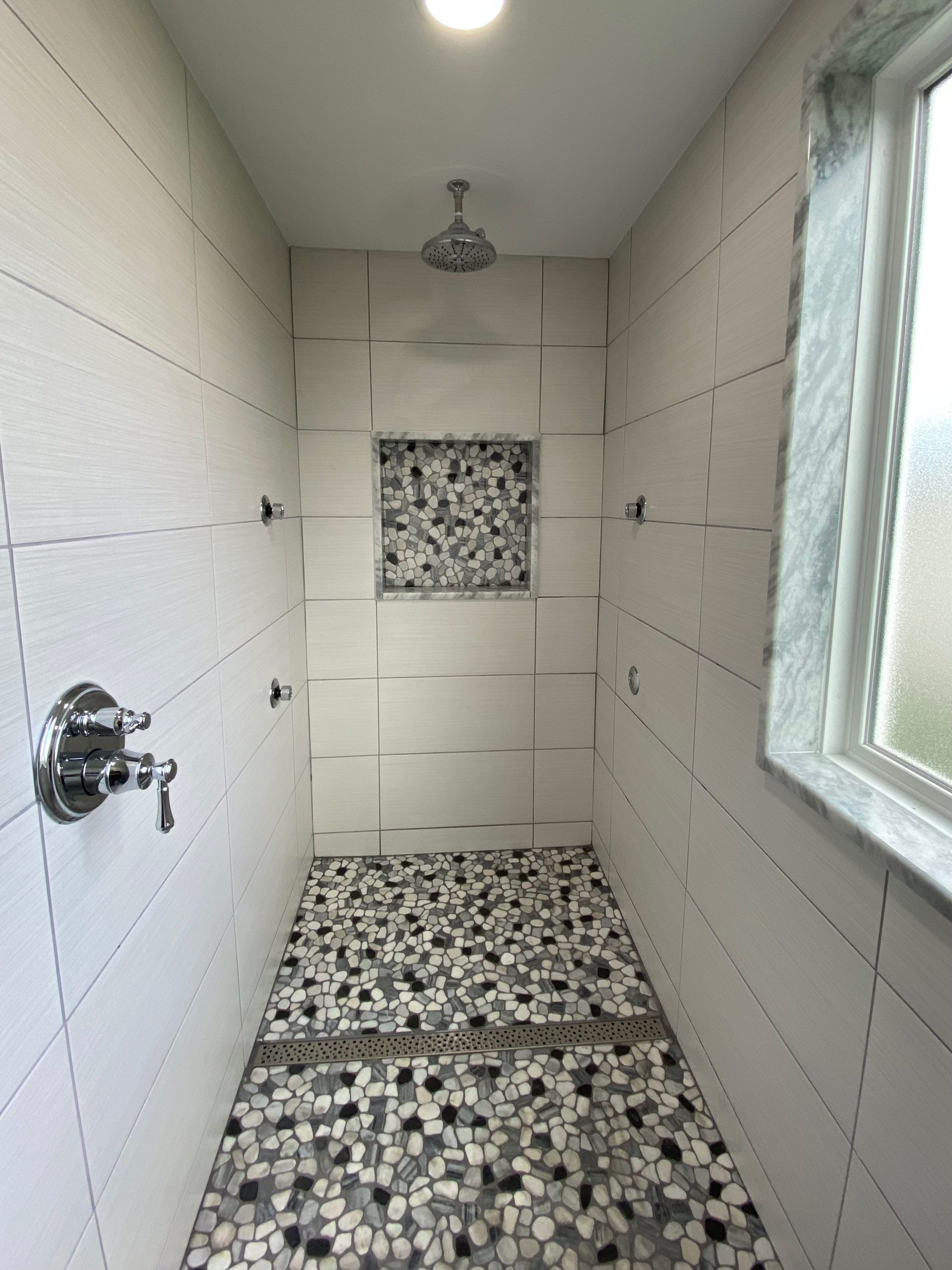 A bathroom with a walk in shower and a window.