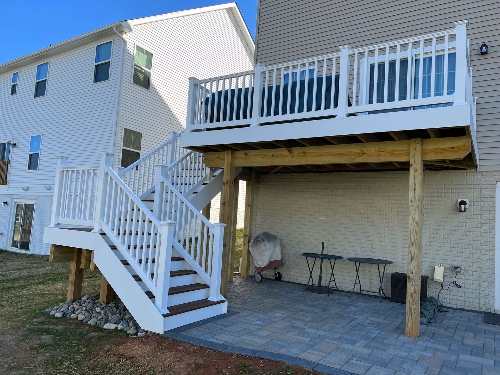 A white deck with stairs leading up to it is in front of a house.