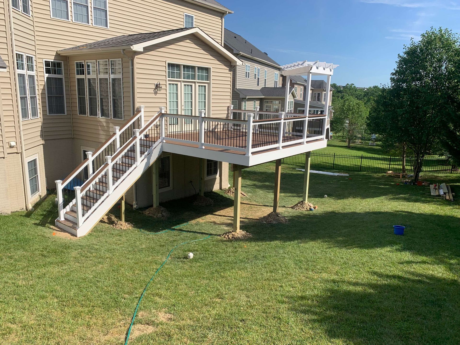 A large deck with stairs leading up to it is in the backyard of a house.