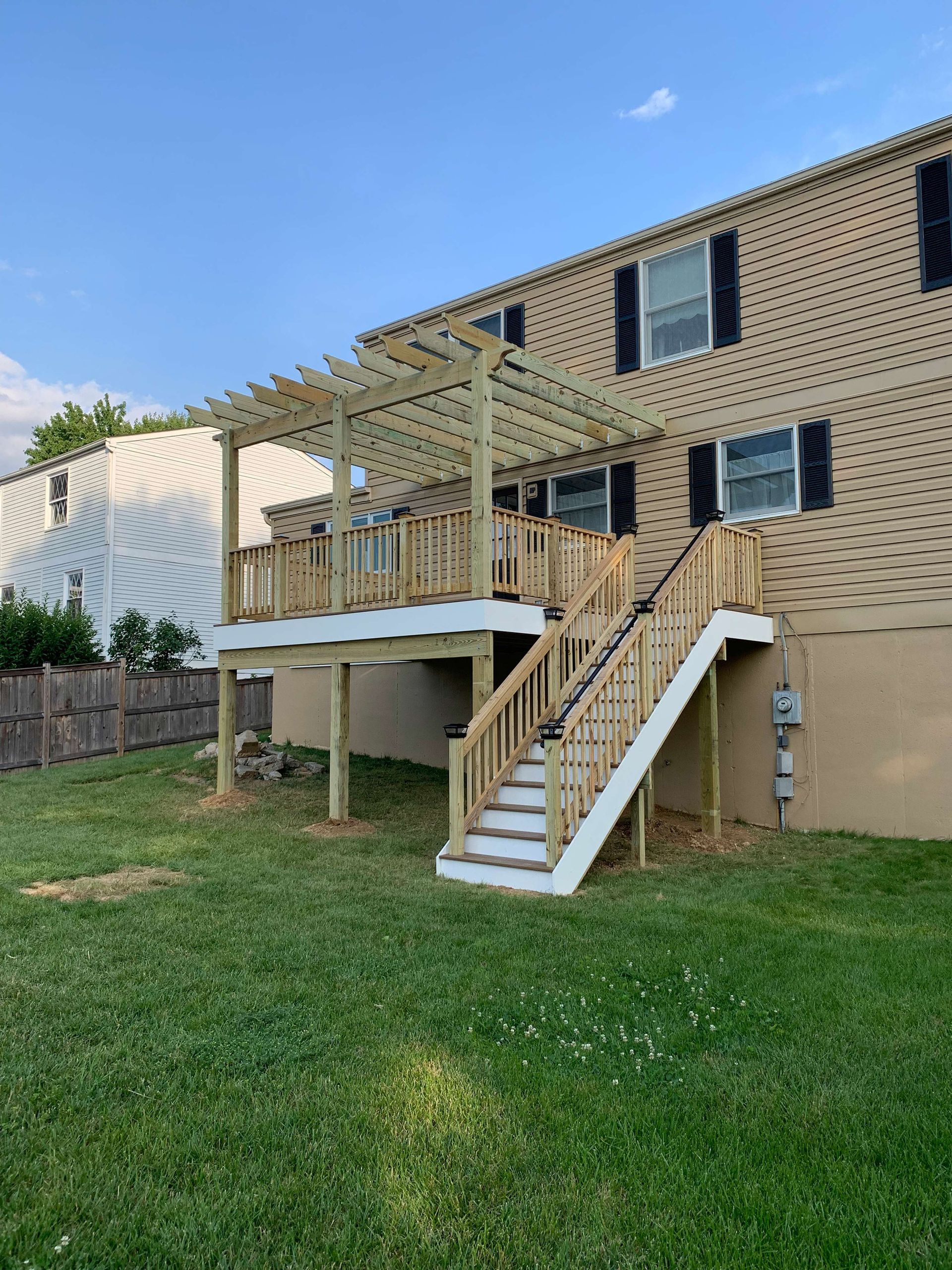 A house with a wooden deck and stairs in the backyard.