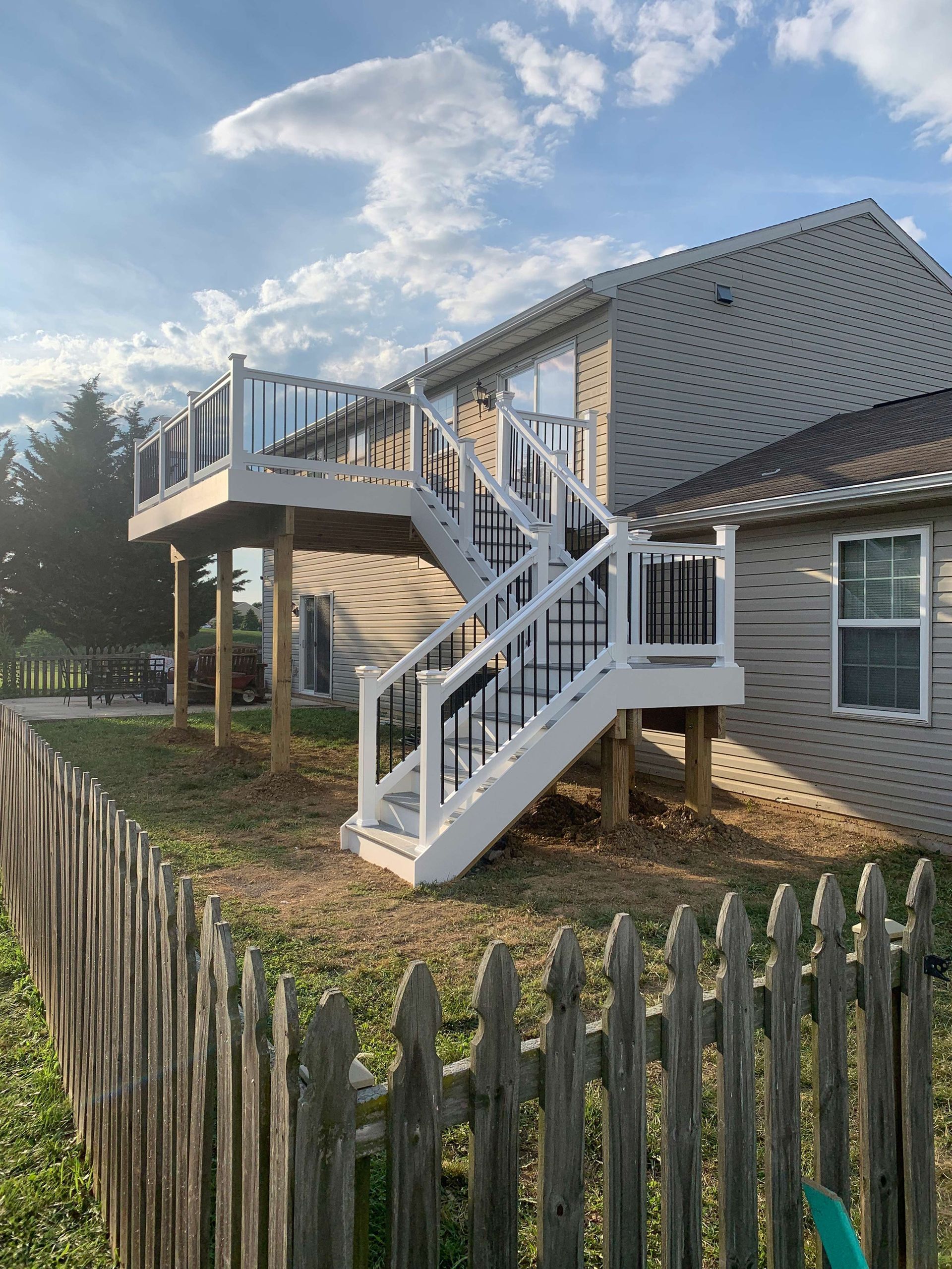 A house with a deck and stairs behind a wooden fence