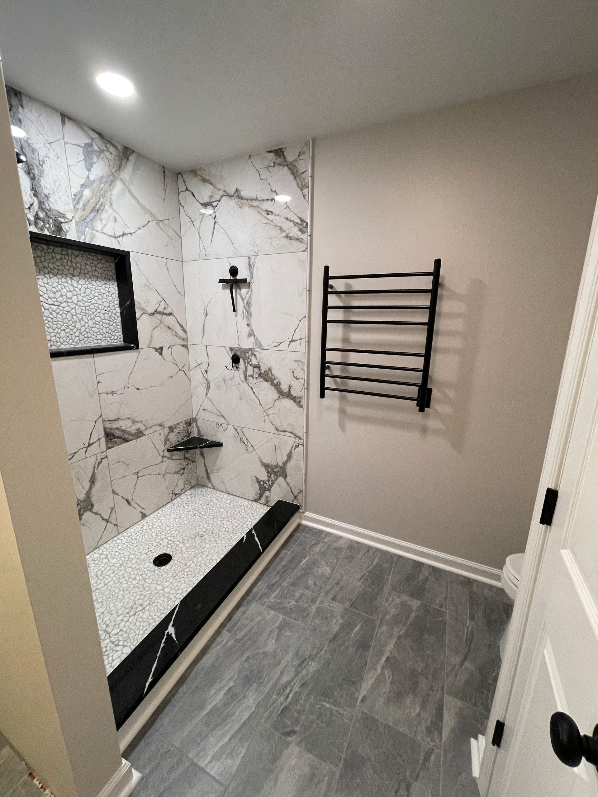 A bathroom with a walk in shower and a towel rack.