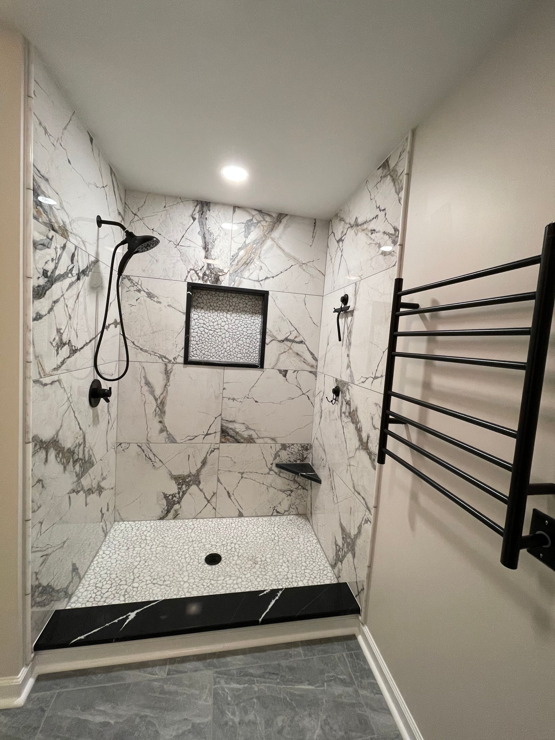 A bathroom with a walk in shower and a towel rack.
