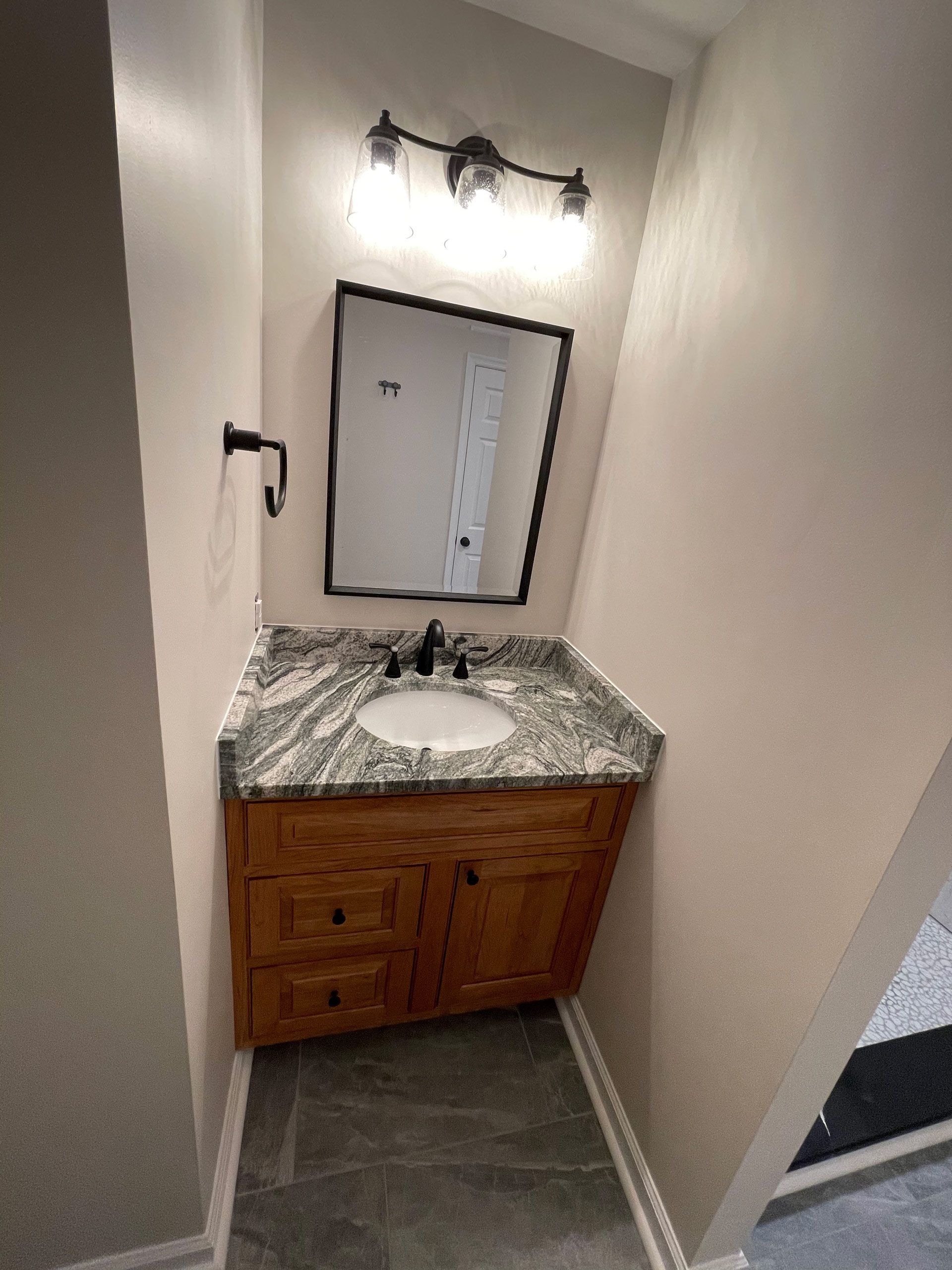 A bathroom with a sink , mirror and light.