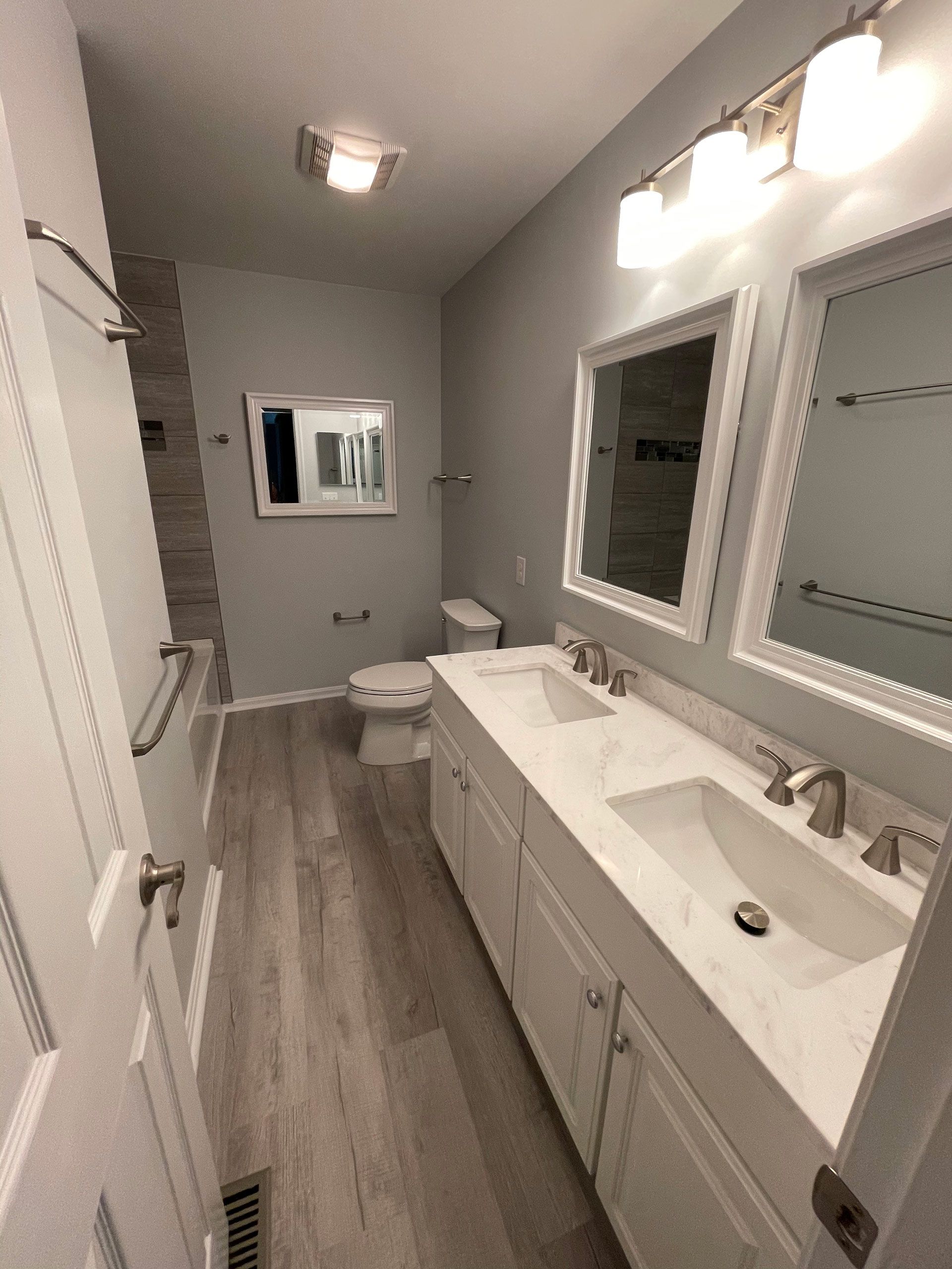 A bathroom with two sinks , a toilet , and two mirrors.