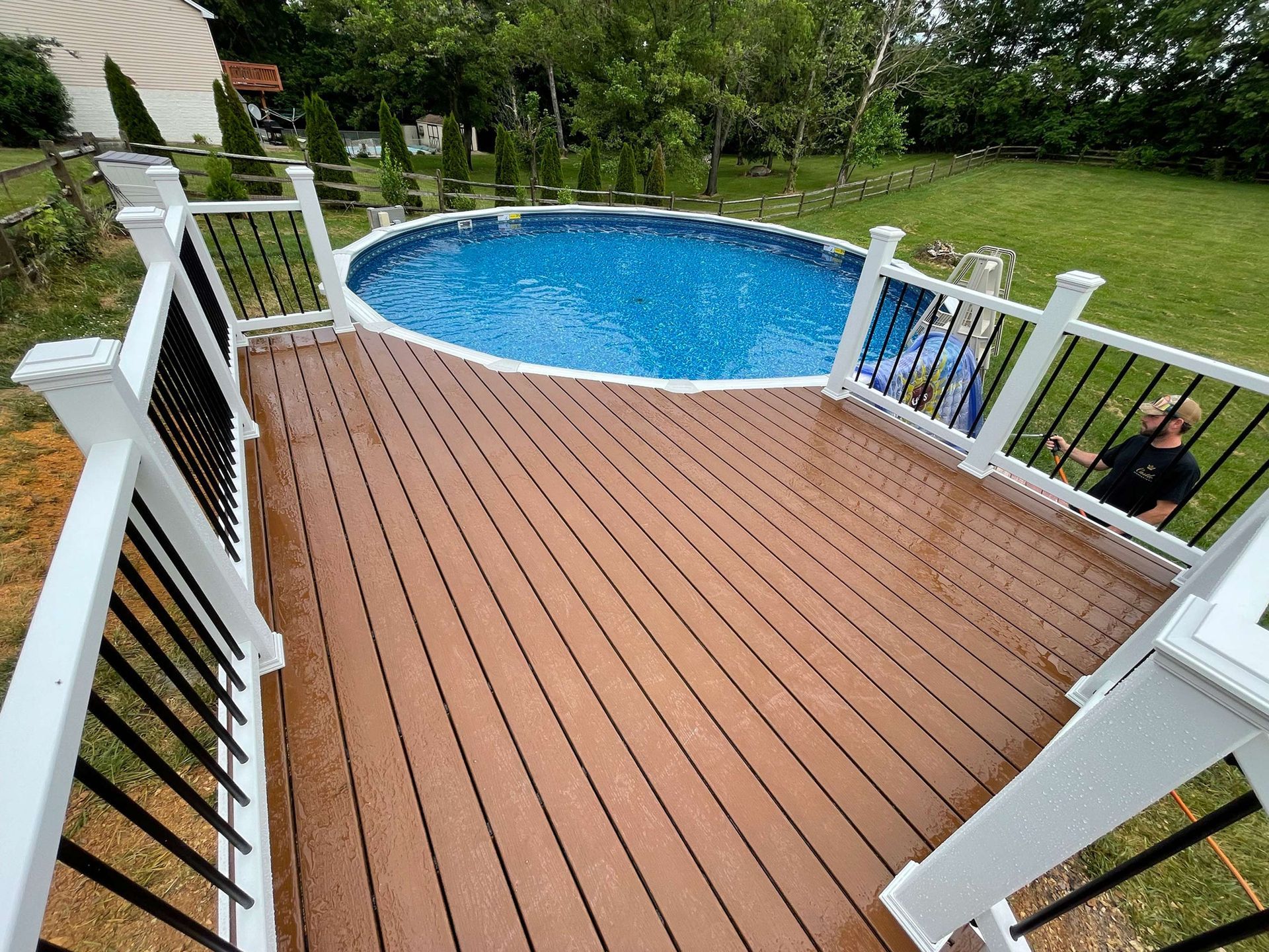 A man is standing on a deck next to a swimming pool.
