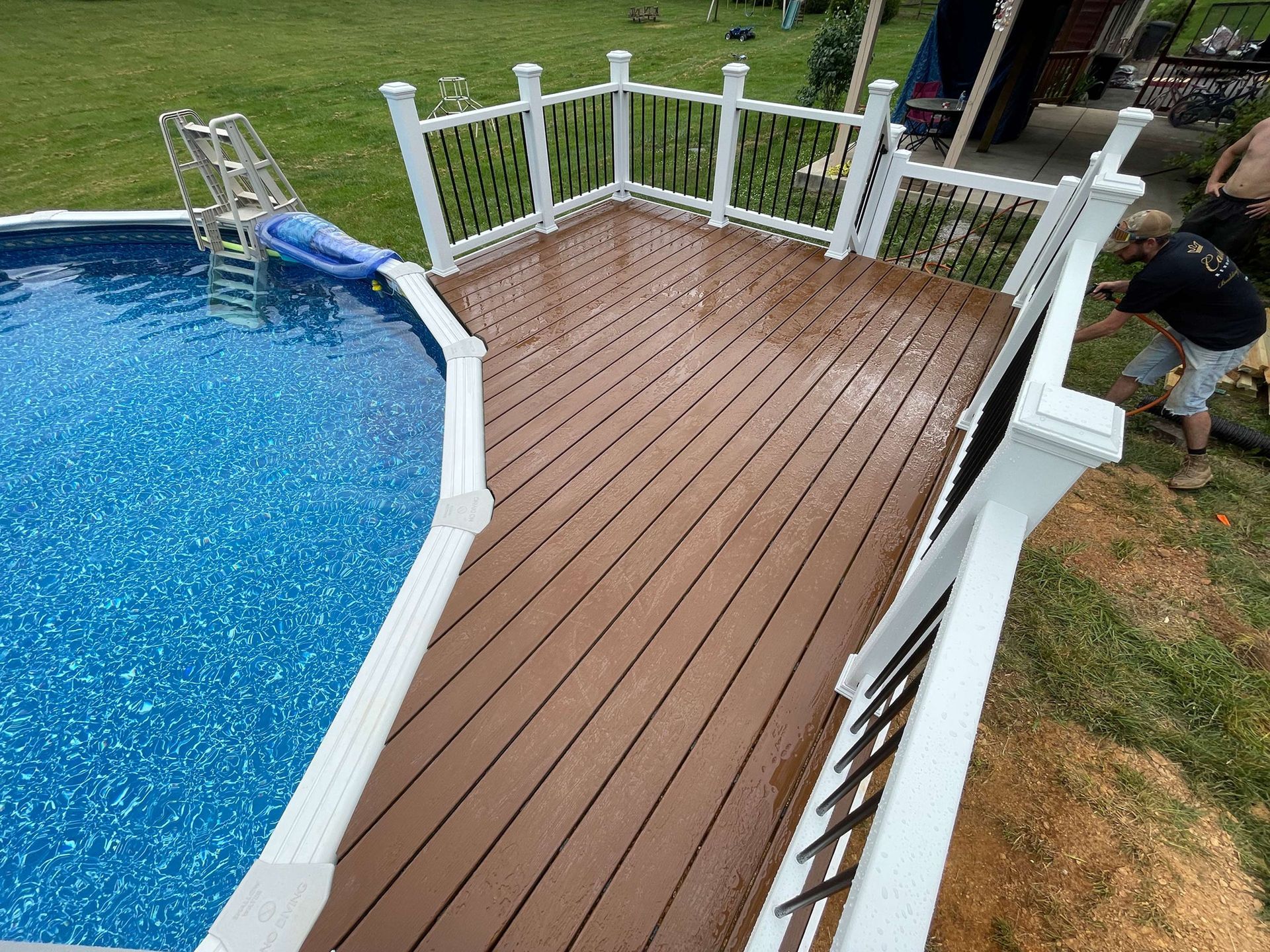A man is working on a deck next to a swimming pool.
