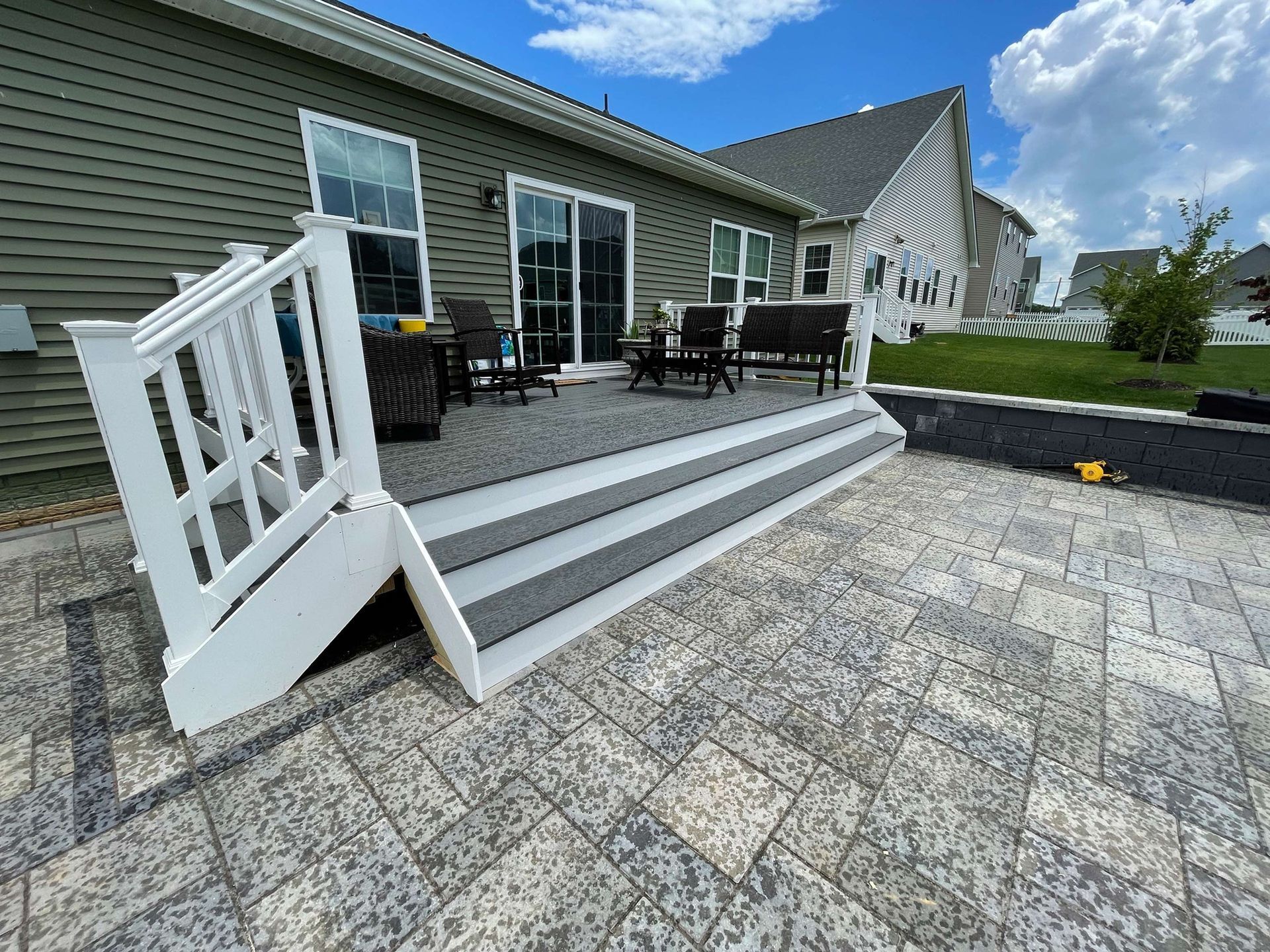 A patio with a white railing and stairs in front of a house.