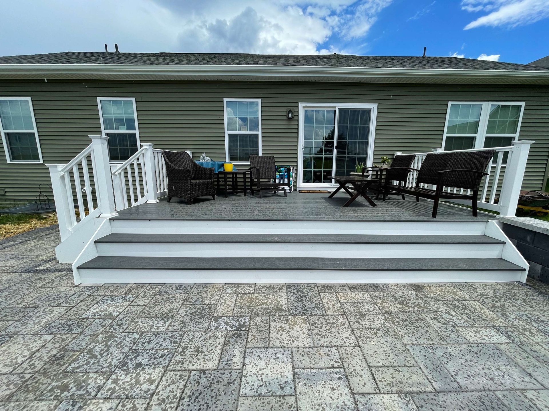 There is a patio with stairs leading up to it in front of a house.