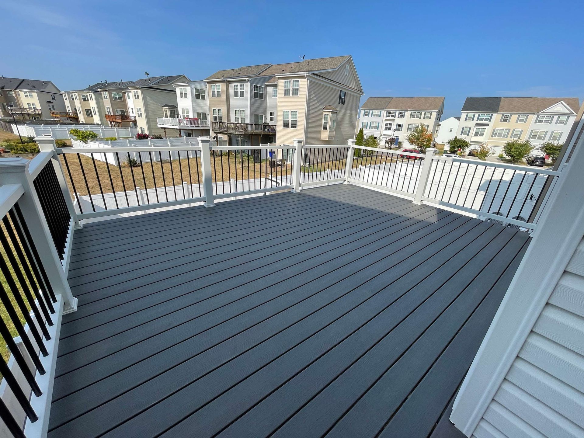A balcony with a gray deck and a white railing