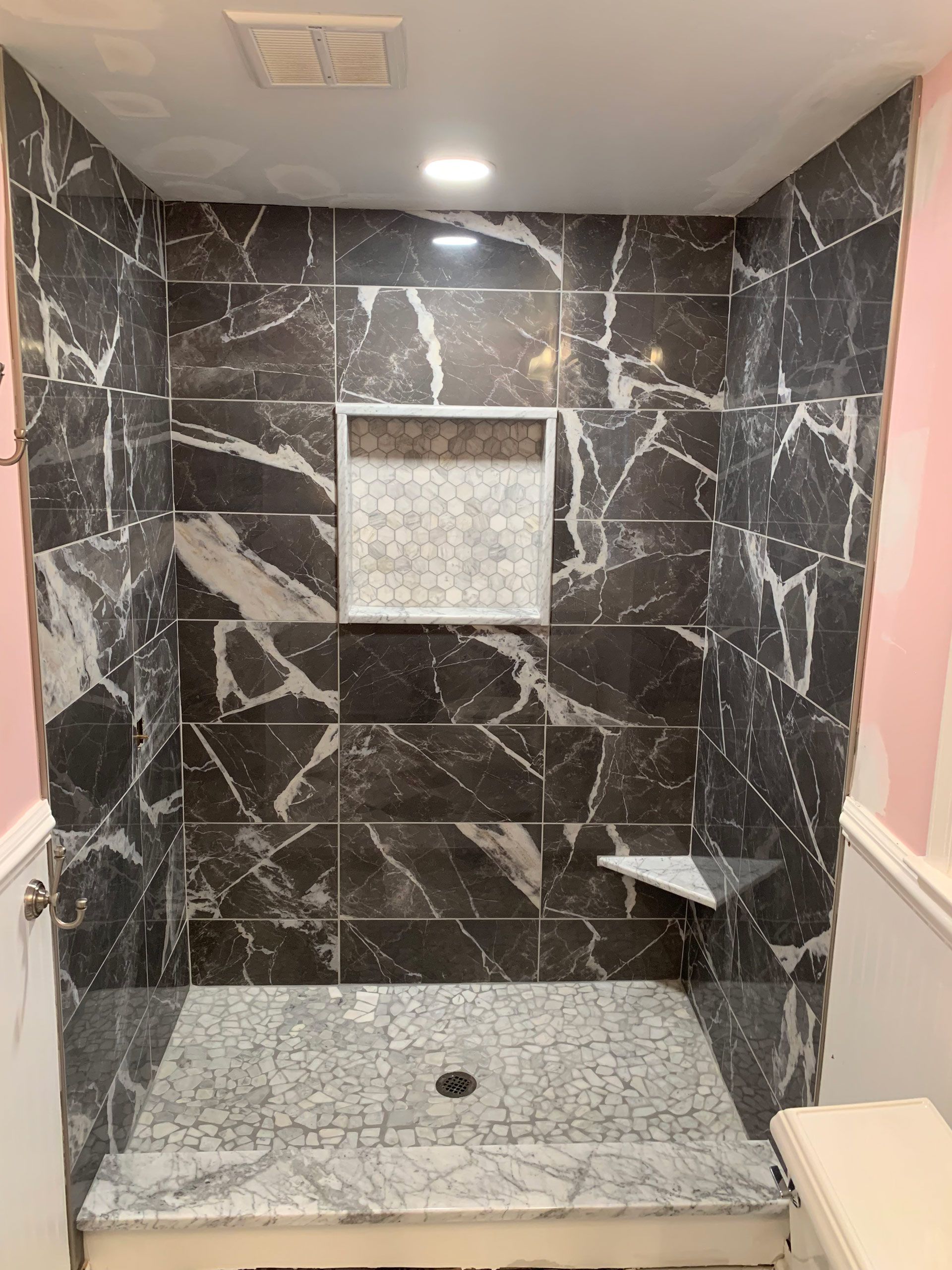 A bathroom with marble tiles and a walk in shower.