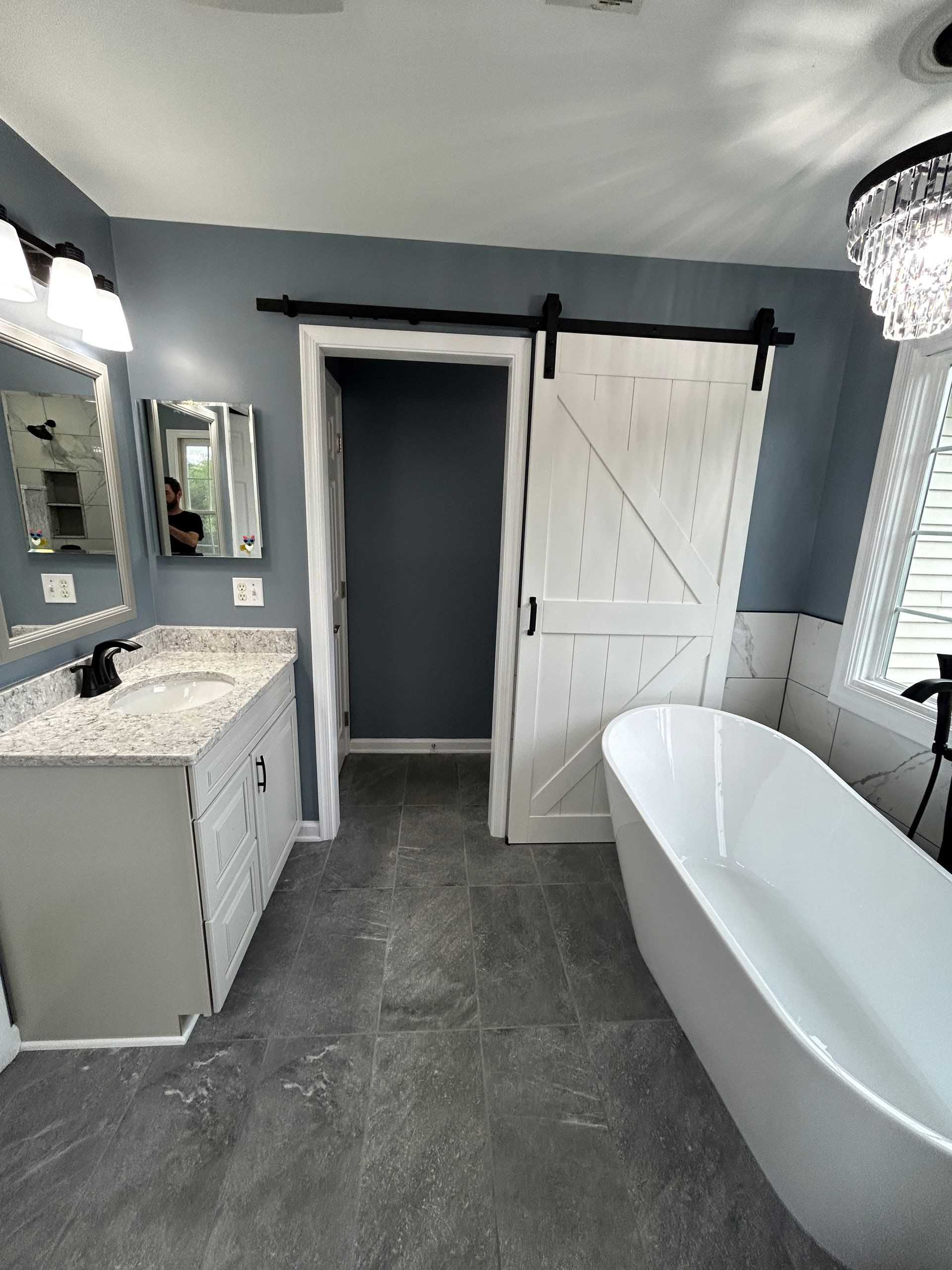 A bathroom with two sinks , a bathtub , and a sliding barn door.