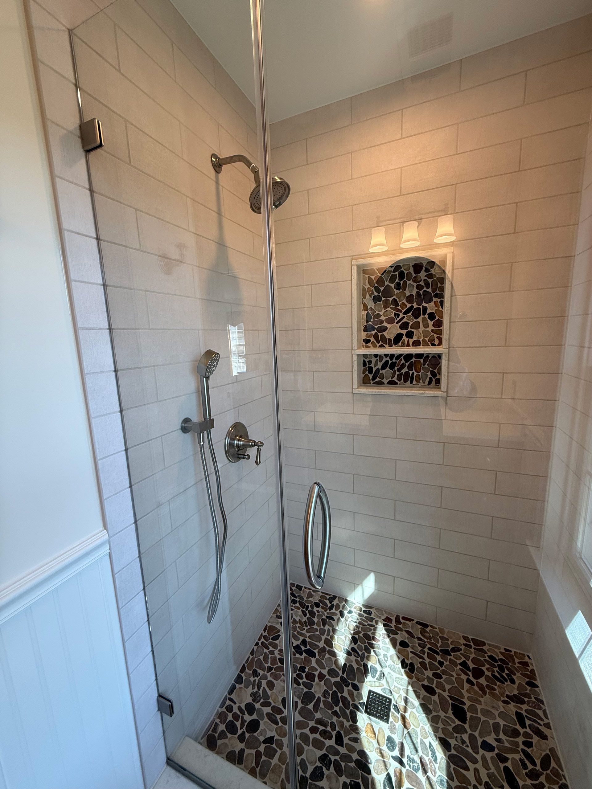 A bathroom with a walk in shower with a glass door.
